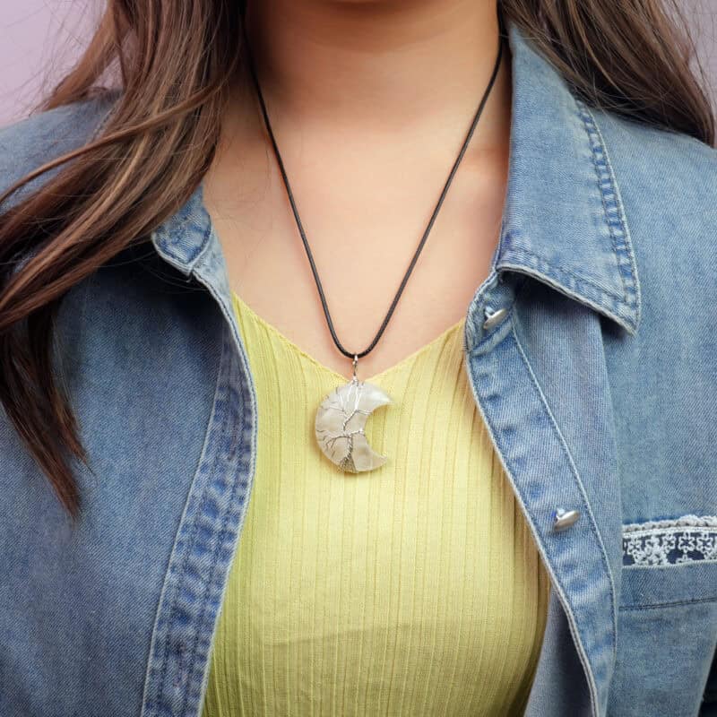 Model wearing clear quartz moon necklace, pendant resting near collarbone
