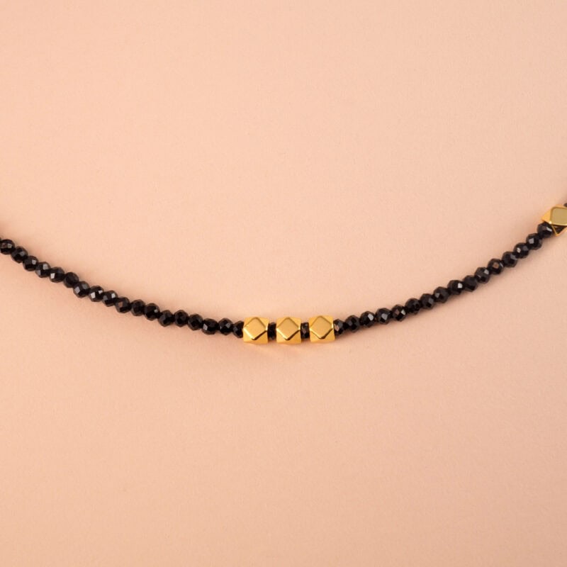 Close-up of polished black obsidian pendant on a gold-plated chain