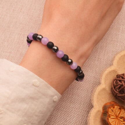 A hand wearing the bracelet, styled with neutral clothing in an everyday setting