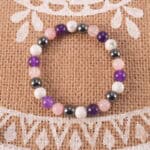 Bracelet resting on a soft pillow by a candle in warm light, symbolizing relaxation and sleep.