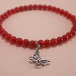 Close-up of red agate beads and silver butterfly charm on 4mm bracelet