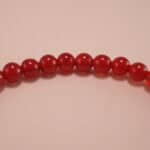 Close-up of red agate beads and silver butterfly charm on 4mm bracelet