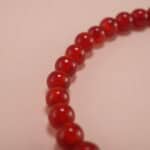 Close-up of red agate beads and silver butterfly charm on 4mm bracelet