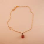 Handmade rose quartz pendant necklace displayed on neutral fabric background