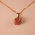 Close-up of rose quartz crystal pendant with silver bail and smooth polish