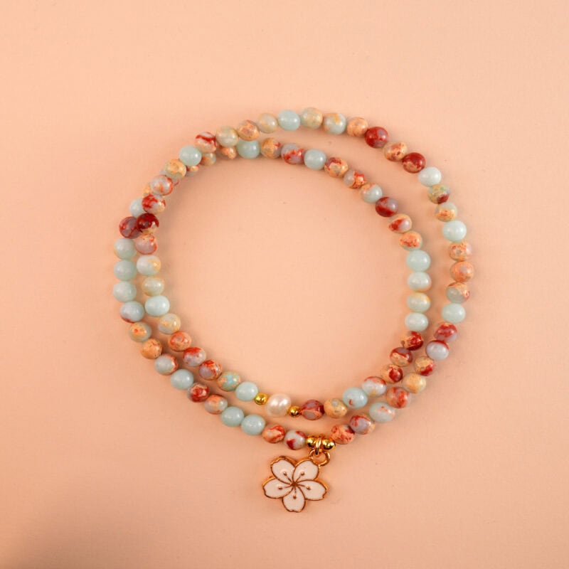 Double layer pearl bracelet with flower charm on white background