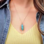 Model wearing the turquoise point pendant at collarbone or heart level