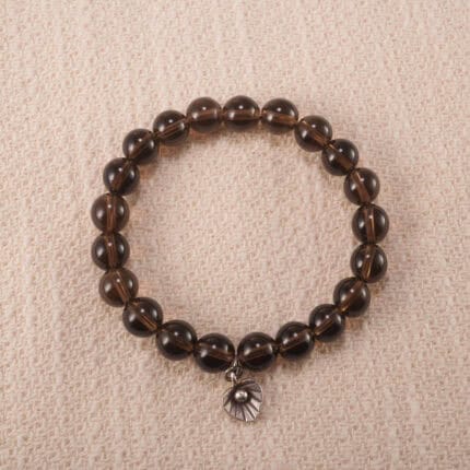 Close-up of a handmade smoky quartz bracelet with 8mm beads and silver flower charm on white background