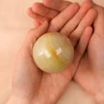 Holding a green jade crystal sphere in hand for calming energy