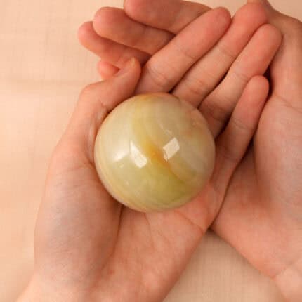 Holding a green jade crystal sphere in hand for calming energy