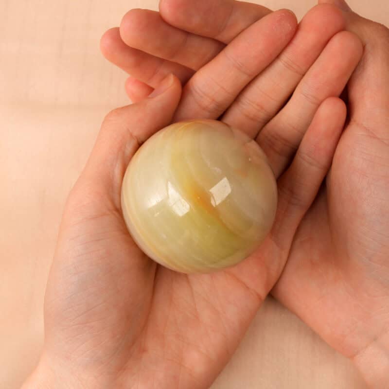 Holding a green jade crystal sphere in hand for calming energy