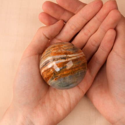 Hand holding the Blue Onyx crystal ball to show its calming color and size