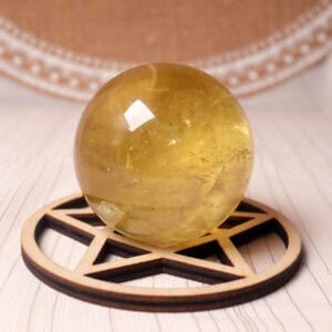 Polished Citrine crystal sphere with golden-yellow glow on display stand