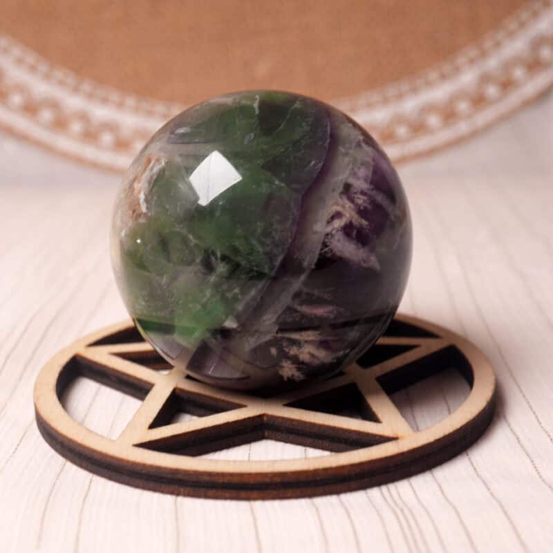 Feather Fluorite crystal sphere with soft purple and green banding on a display stand