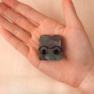 Hand holding Fluorite hedgehog figurine, showing color gradient and small size