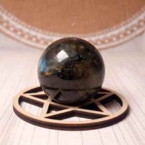 Polished labradorite crystal sphere with colorful flash on white background