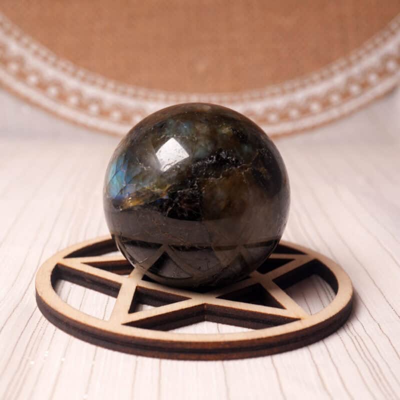 Polished labradorite crystal sphere with colorful flash on white background