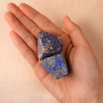 Hand holding a piece of raw Lapis Lazuli, highlighting its natural texture and rich blue color.