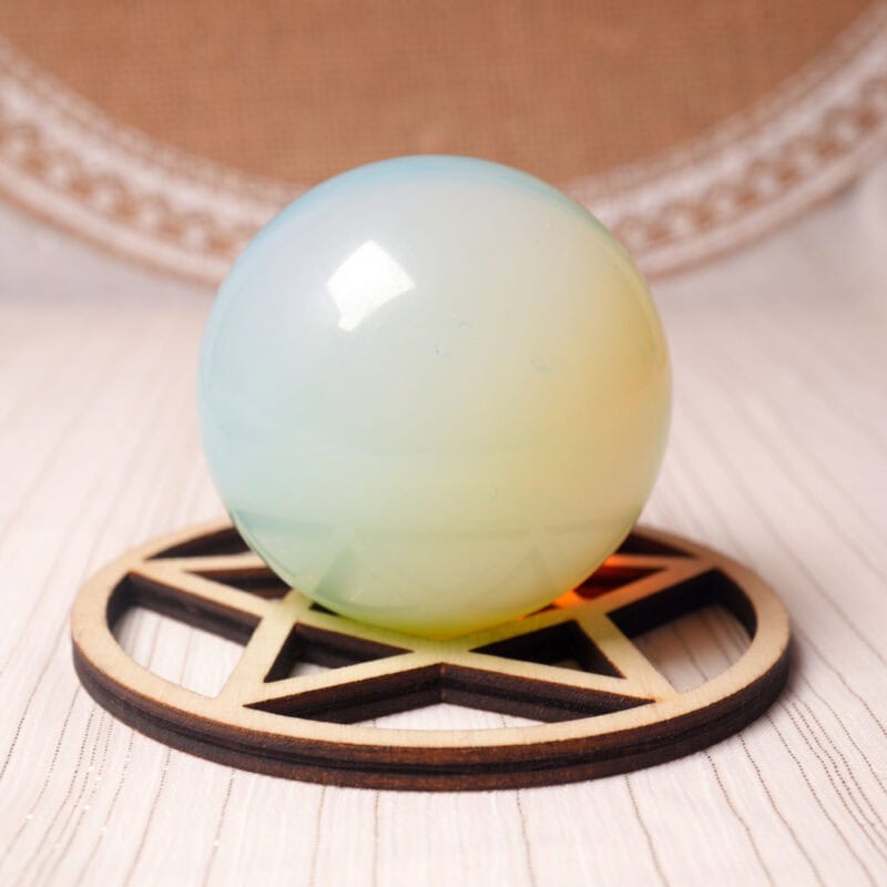 Polished opal crystal sphere with pastel glow on clean background