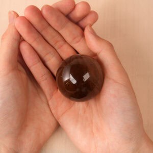 Hand holding the Smoky Quartz sphere, showing its size and clarity