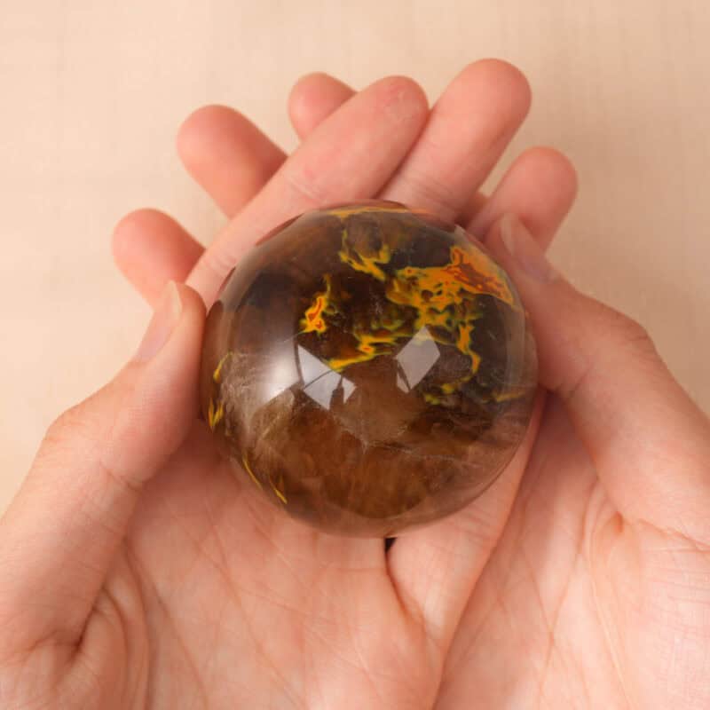 Hand holding the crystal ball to show size and shimmering detail