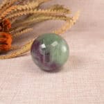 Fluorite sphere displayed near books, candles, or protective crystals