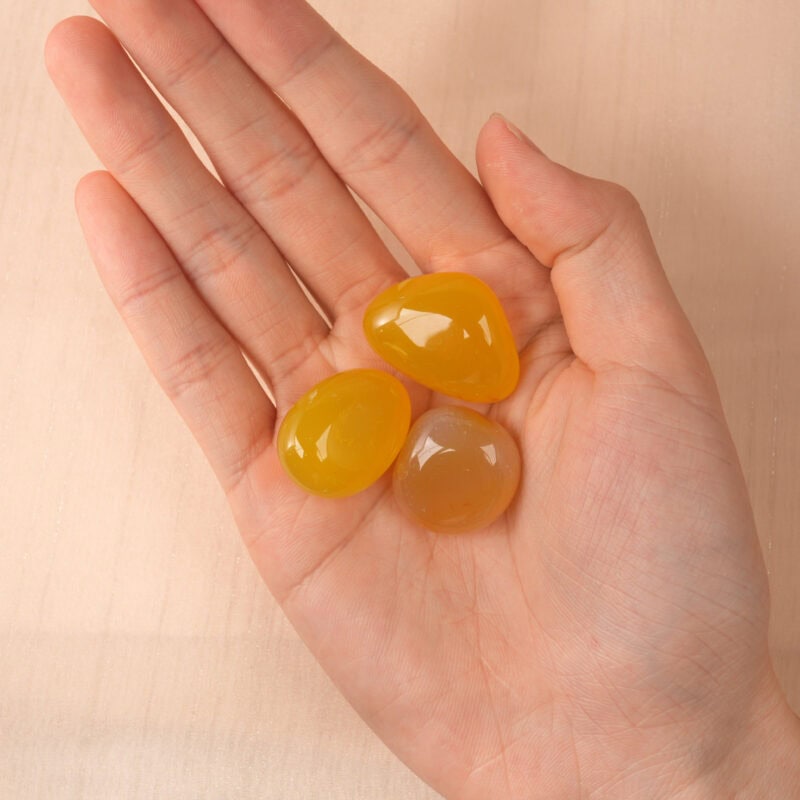 Person holding a Natural Yellow Agate Tumbled Stone Set, showcasing the polished yellow stones, perfect for meditation and energy work.