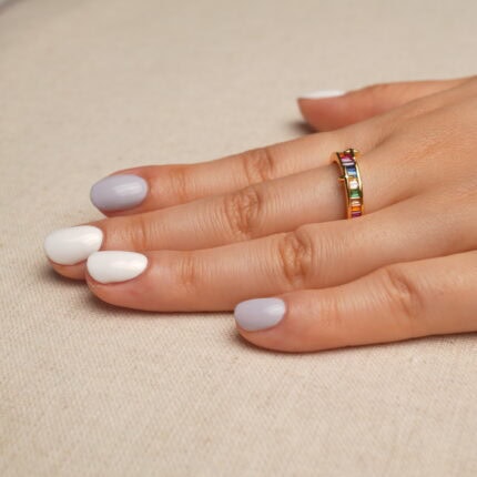 Hand holding the Rainbow Ring showcasing its colorful zircon gemstones and polished design