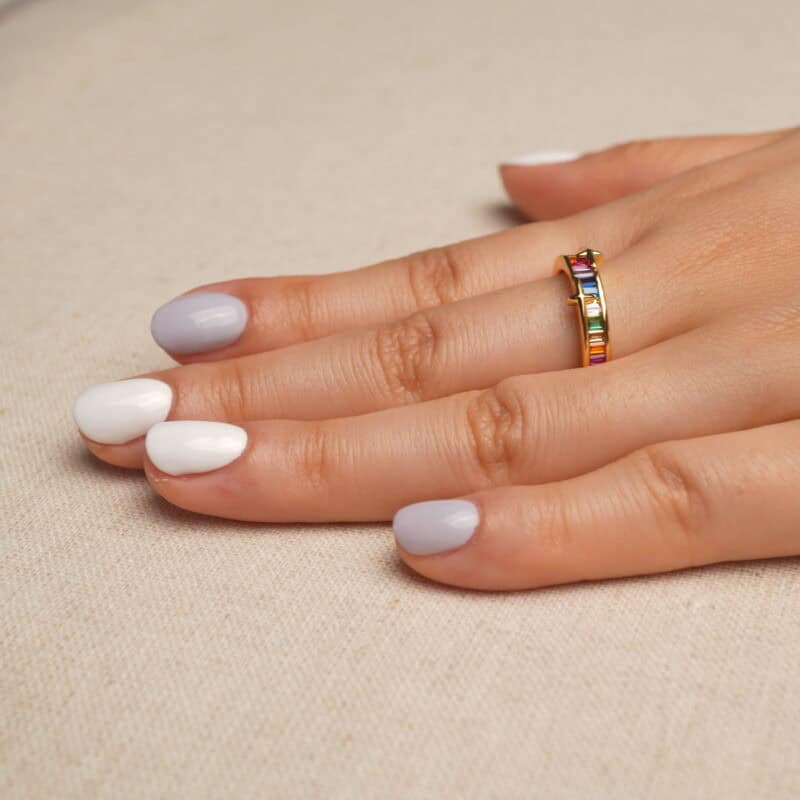 Hand holding the Rainbow Ring showcasing its colorful zircon gemstones and polished design