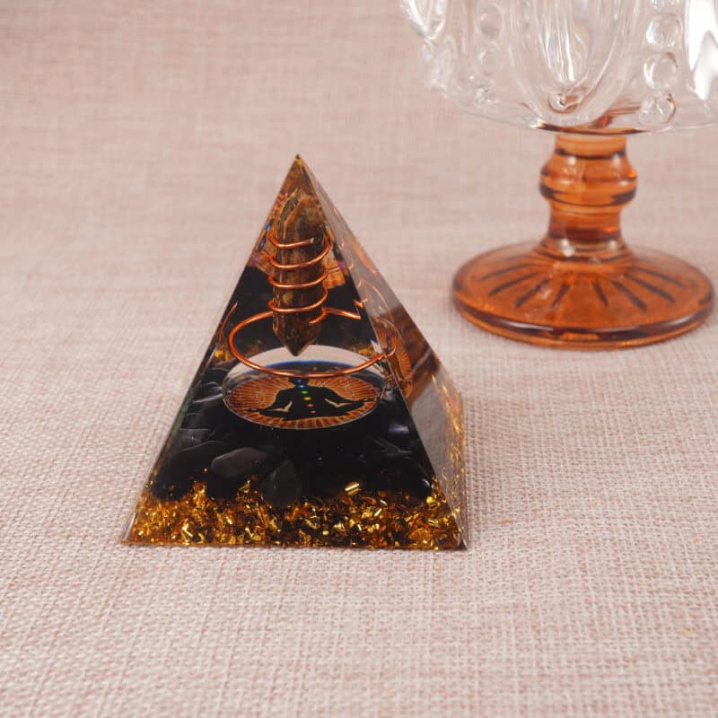 Tiger Eye and Obsidian pyramid displayed on wooden desk with crystals and meditation candles
