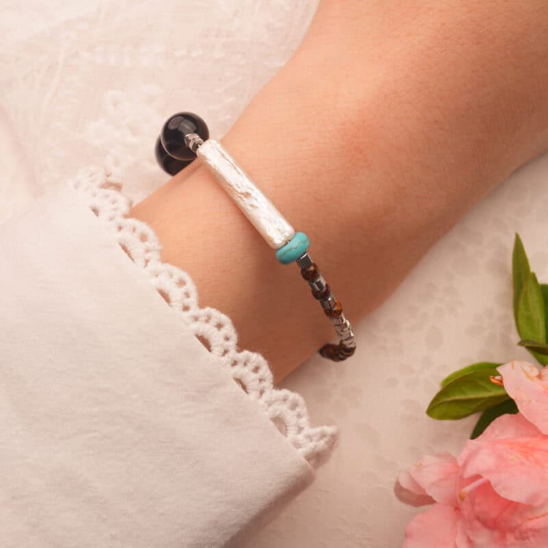 Woman wearing tiger eye and turquoise bracelet with casual boho outfit, symbolizing strength and protection