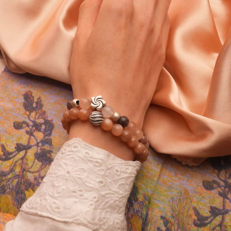 Model wearing peach moonstone and aventurine S925 bracelets on wrist.