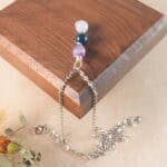 Aquarius zodiac necklace displayed on wooden board with amethyst, blue apatite, and aquamarine.