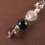 Close-up of Capricorn necklace showing clear quartz, obsidian, and smoky quartz beads.