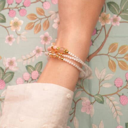 Model wearing the piece as a triple-layer bracelet around the wrist.