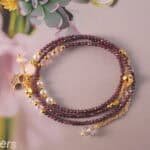 Full view of the necklace laid out, showing the garnet beads and minimalist design.