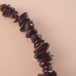 Close-up of polished garnet, lustrous pearl, and translucent aquamarine beads strung on durable elastic cord.