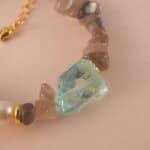 Close-up of the intricate textures in the skeleton quartz bead, beside polished pearl and aquamarine accents.