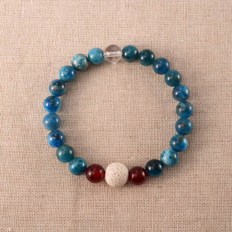 Handmade bracelet with Lava Stone, Red Agate, and Blue Fluorite beads arranged on a neutral background.