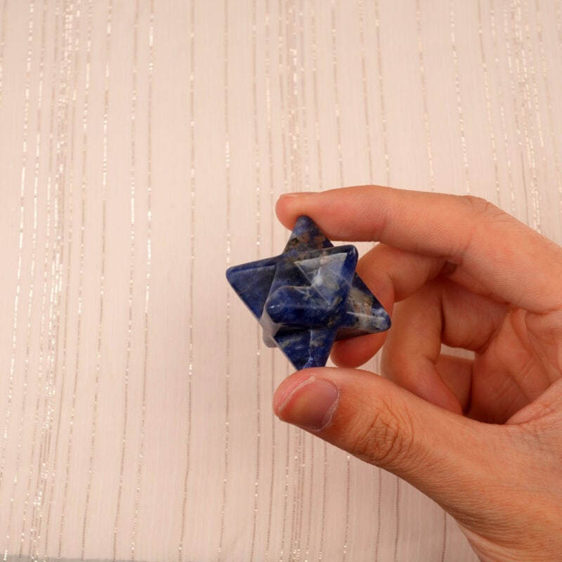 The Lapis Lazuli Merkaba ornament resting on a hand, highlighting its size and crystal clarity.