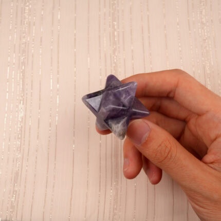 Dream Amethyst Merkaba ornament held in hand, showcasing its smooth polish and natural crystal patterns.