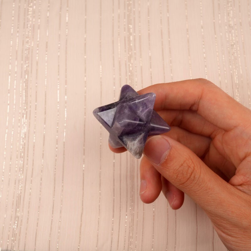 Dream Amethyst Merkaba ornament held in hand, showcasing its smooth polish and natural crystal patterns.