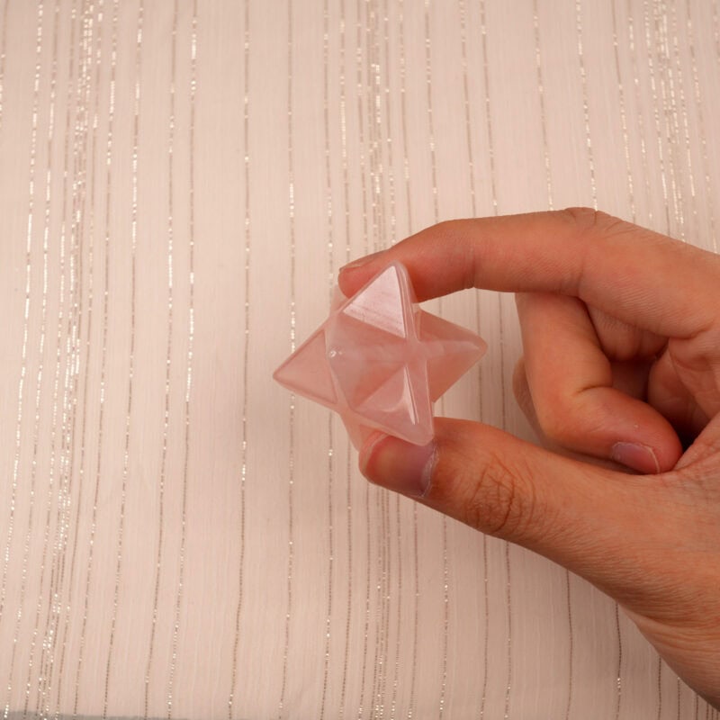 Hand holding a Rose Quartz Merkaba crystal, highlighting its gentle color and compact size.
