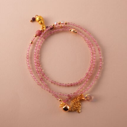 A soft pink-toned multi-use necklace made with rose quartz and rhodochrosite beads, arranged in a spiral display.