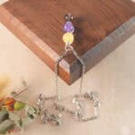 Sagittarius zodiac necklace displayed on wooden board with yellow chalcedony, amethyst, and smoky quartz.