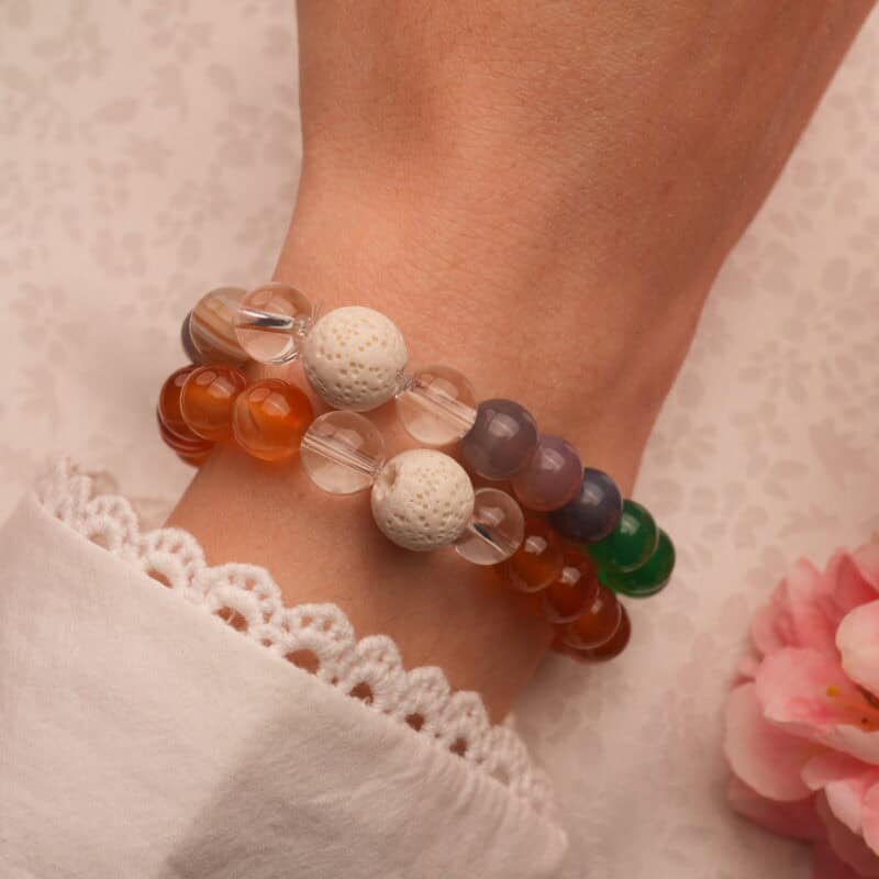 Model wearing stacked agate bracelets with quartz highlights.