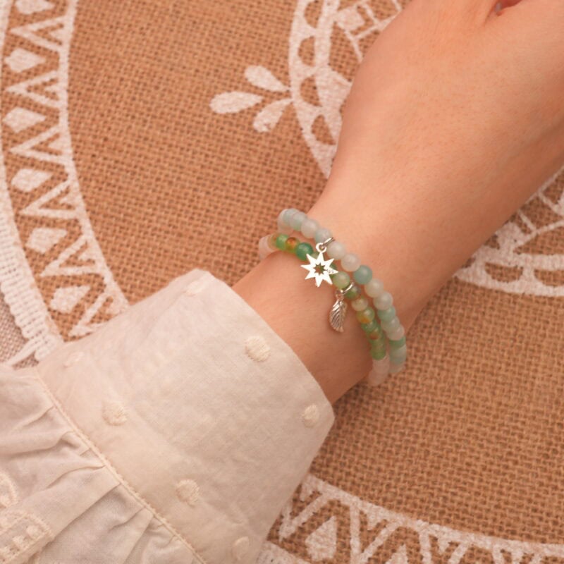 Model wearing stacked gemstone bracelets in aqua and pastel tones.