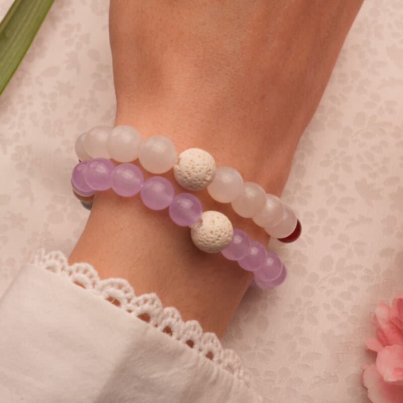Model wearing gemstone bracelet stack with lava textures.