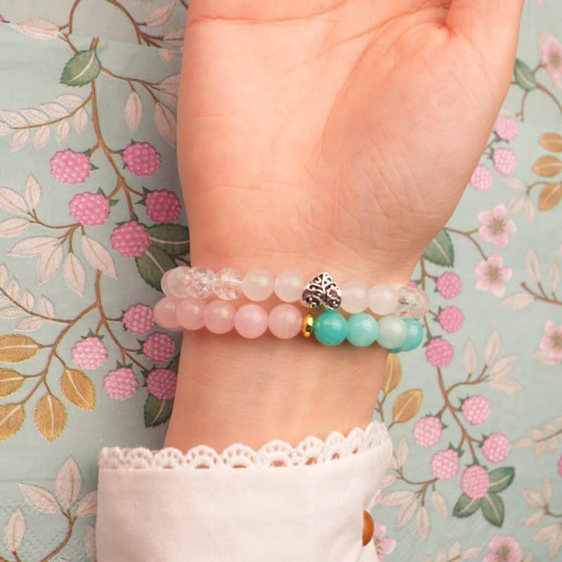 Model wearing gemstone bracelet stack in soft, feminine colors.