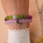 Model wearing stacked amethyst and tourmaline bracelets on wrist.